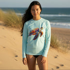Cute Teen in Light blue long-sleeve swimming rashie with a colorful turtle design standing on sand dunes on a Florida Beach