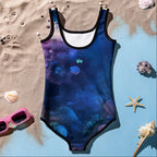 Back of Girl's One Piece Dolphin Swimsuit lying in the sand next to sunglasses and seashells