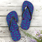 Purple flip-flops with teal dolphin pattern on a wooden surface with flowers.