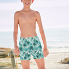 Teen Dude wearing palm tree patterned swim shorts on a beach