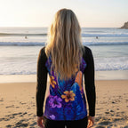 Person wearing a colorful hibiscus floral sun rashie, watching surfers from the La Jolla Cove Beach 