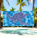Tie Dye Beach Towel with Zen Sea Turtle Design hanging on a line in a tropical beach paradise