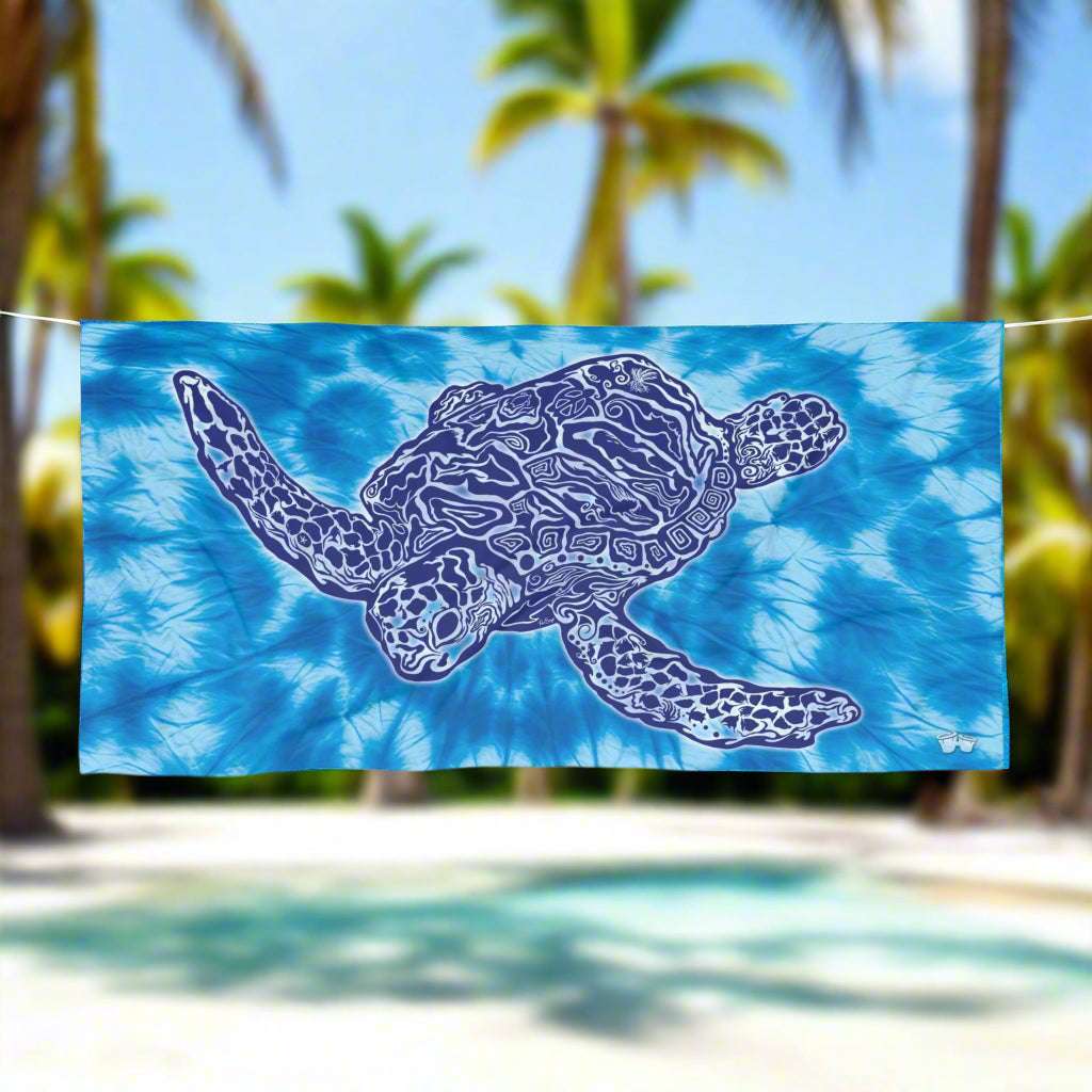 Tie Dye Beach Towel with Zen Sea Turtle Design hanging on a line in a tropical beach paradise