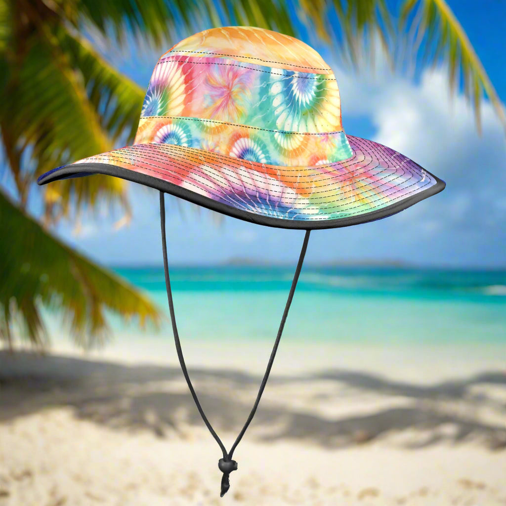 Colorful tie-dye bucket hat with a black chin strap on a white sandy beach background