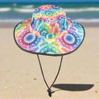 Colorful tie-dye floppy bucket hat with a black strap on a beach background
