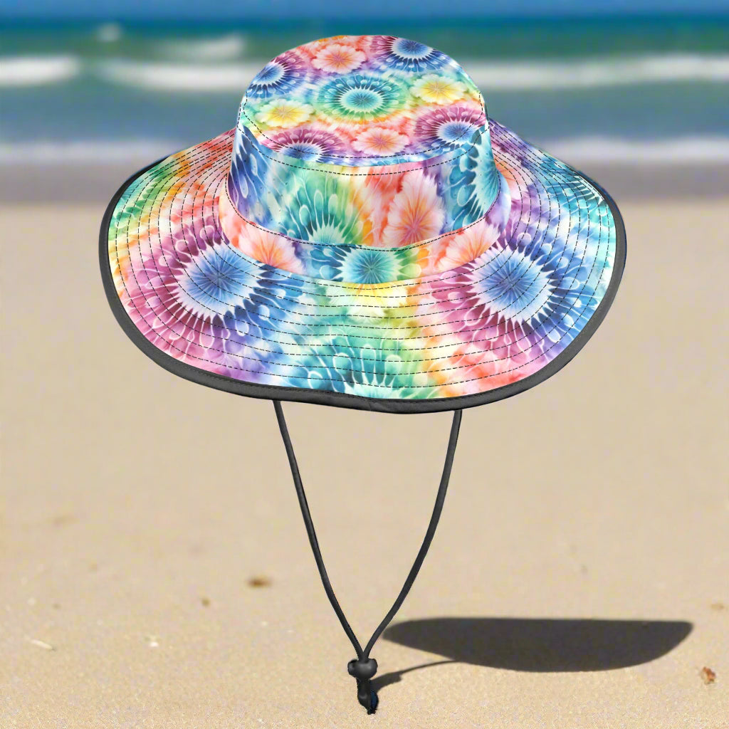 Colorful tie-dye floppy bucket hat with a black strap on a beach background