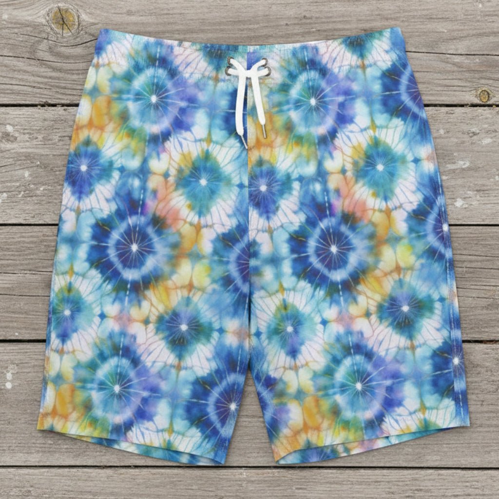 close up of tie dye printed board shorts laying flat on a rustic nautical wood deck