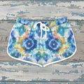 Colorful tie-dye shorts with a white drawstring on a rustic nautical wood background