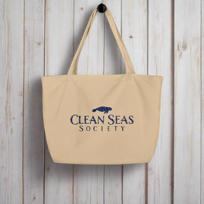 Large organic tote bag from Clean Seas Society hanging on a rustic nautical wood wall