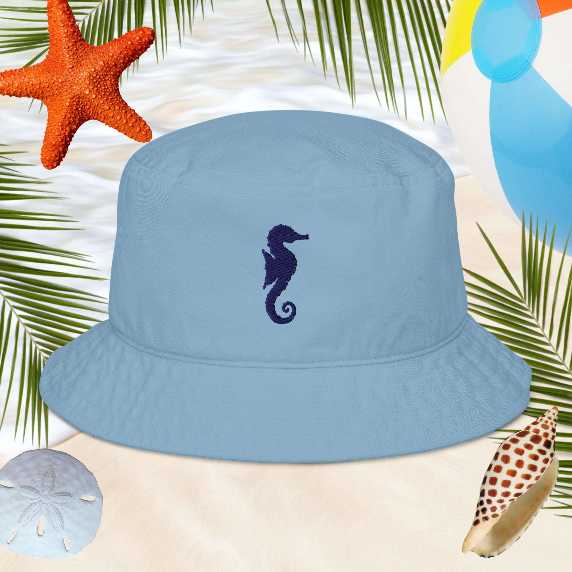 Blue cotton bucket hat with a seahorse embroidery on a beach-themed background with starfish and palm leaves.