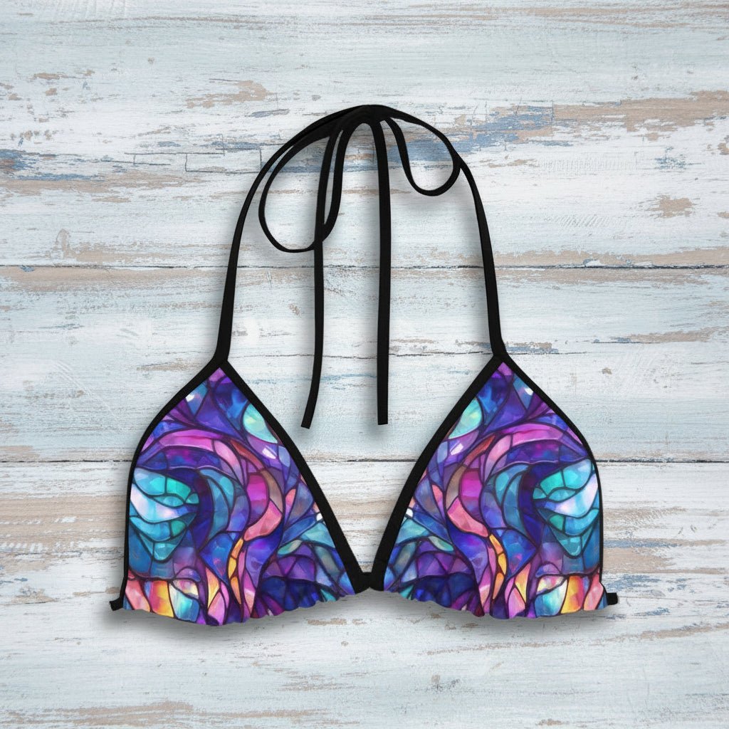 Colorful bikini top with a black halter strap on a rustic wood background