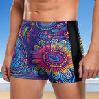 Colorful patterned swim shorts with a black side panel against a beach background