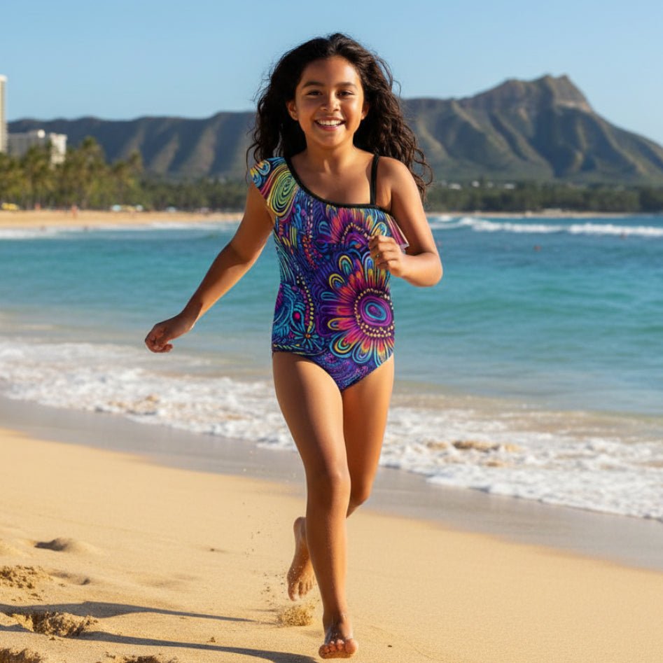 Cute little girl wearing a Colorful one-piece swimsuit with a vibrant pattern running and playing on Waikiki Beach