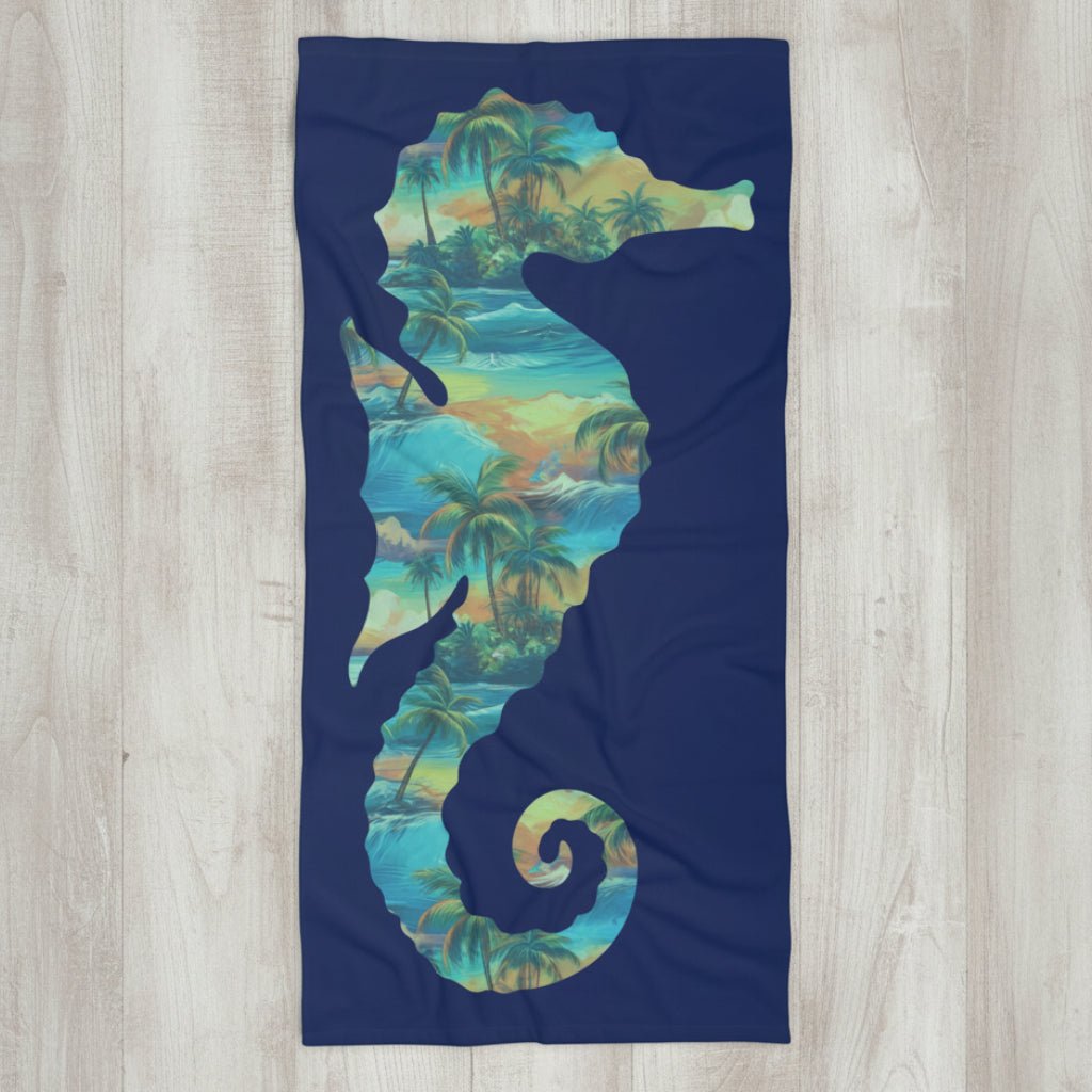 A rectangular beach towel with a dark navy blue background, featuring a large silhouette of a seahorse filled with a tropical palm tree and wave pattern in shades of teal, green, and yellow.