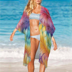 Woman on a beach wearing a colorful kimono-style cover-up with a blue ocean background