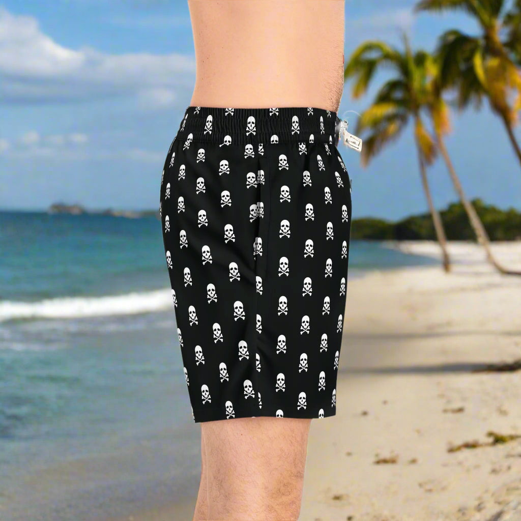 Dude wearing Pirate skull and crossbones board short standing on the beach