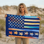 Person holding a colorful American flag with turtle designs on a beach