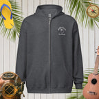 Dark gray hoodie with a logo on a wooden background with tropical elements.