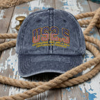 Blue denim cap with 'US25' text and American flag design on a wooden surface with rope.