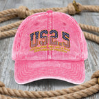 Pink cap with 'US25' text and American flag design on a wooden surface with rope.