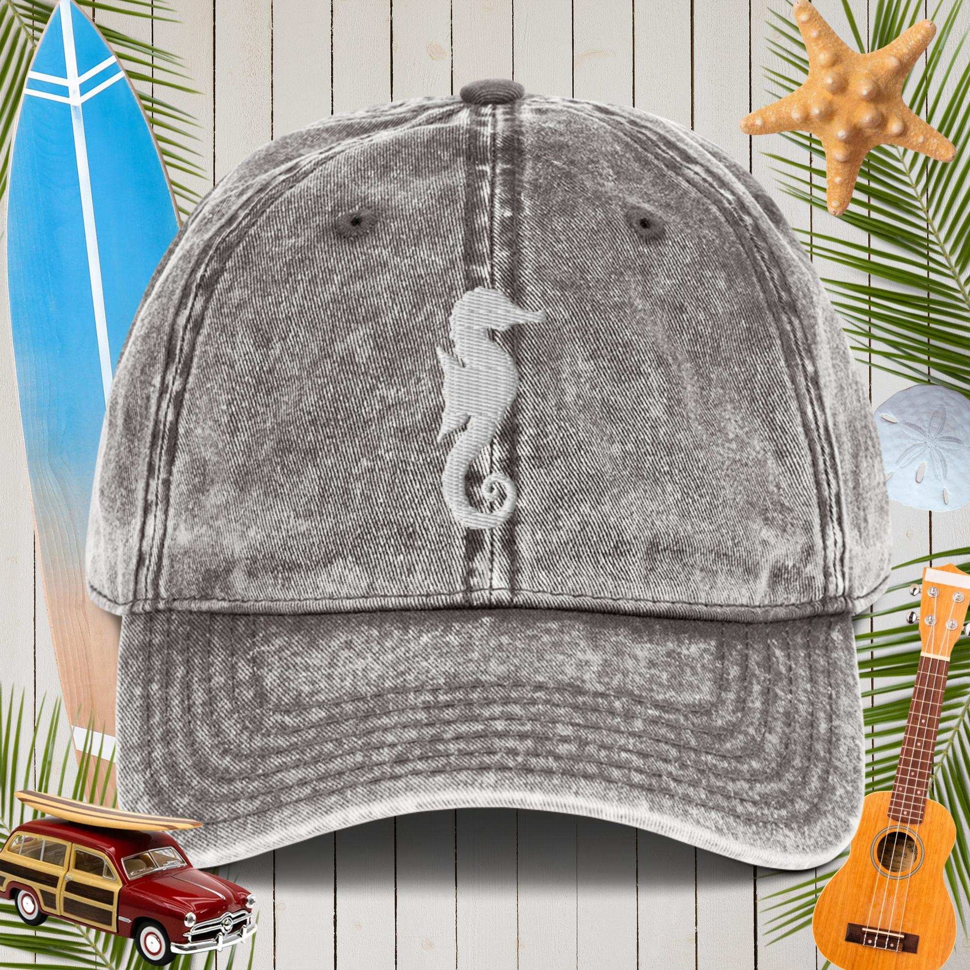 Gray cap with a seahorse design on a wooden background with beach-themed items.