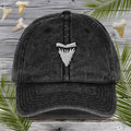 Black cap with a white Embroidered Shark Tooth on a wooden background with shark fins and palm leaves.