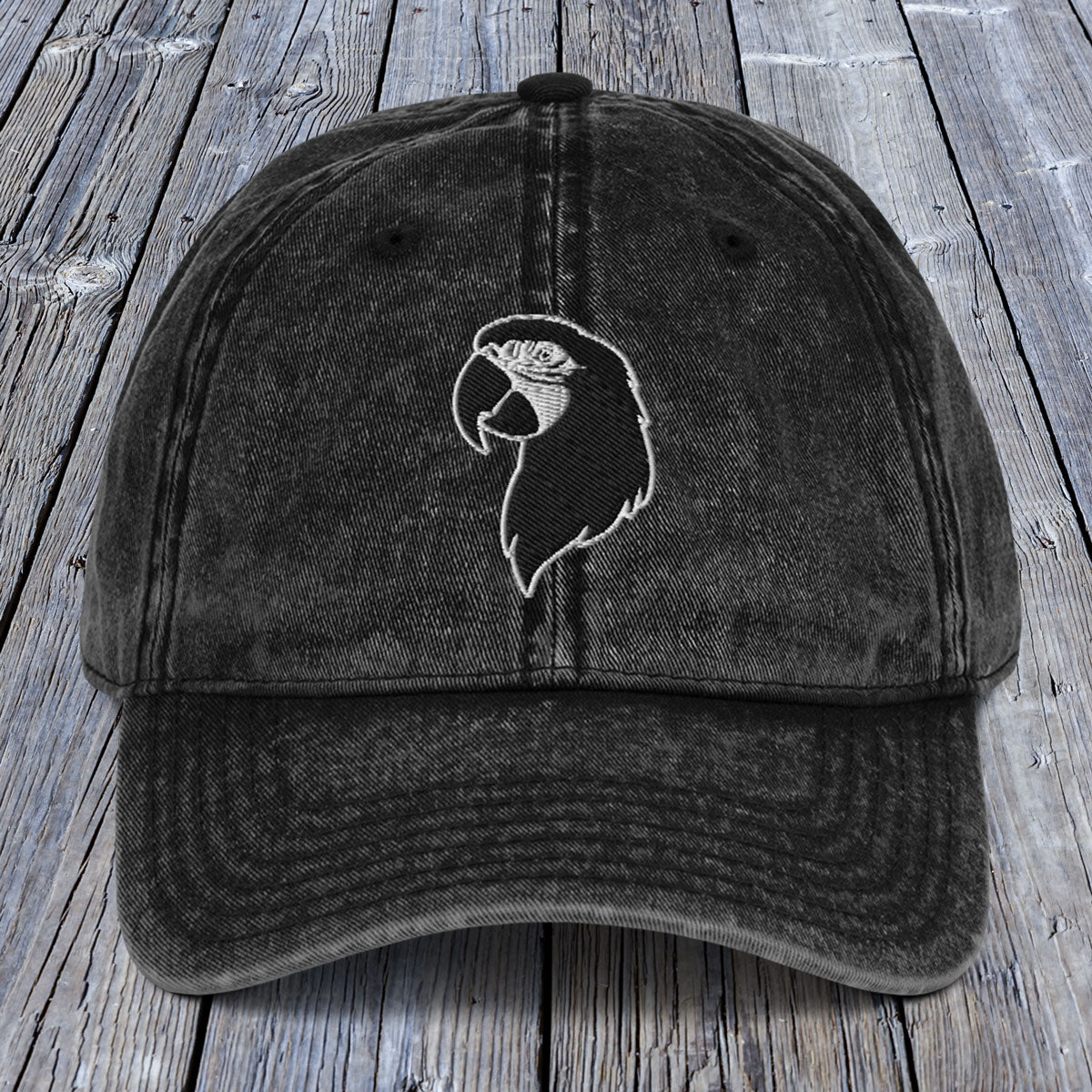 Black cap with a white parrot design on a wooden surface
