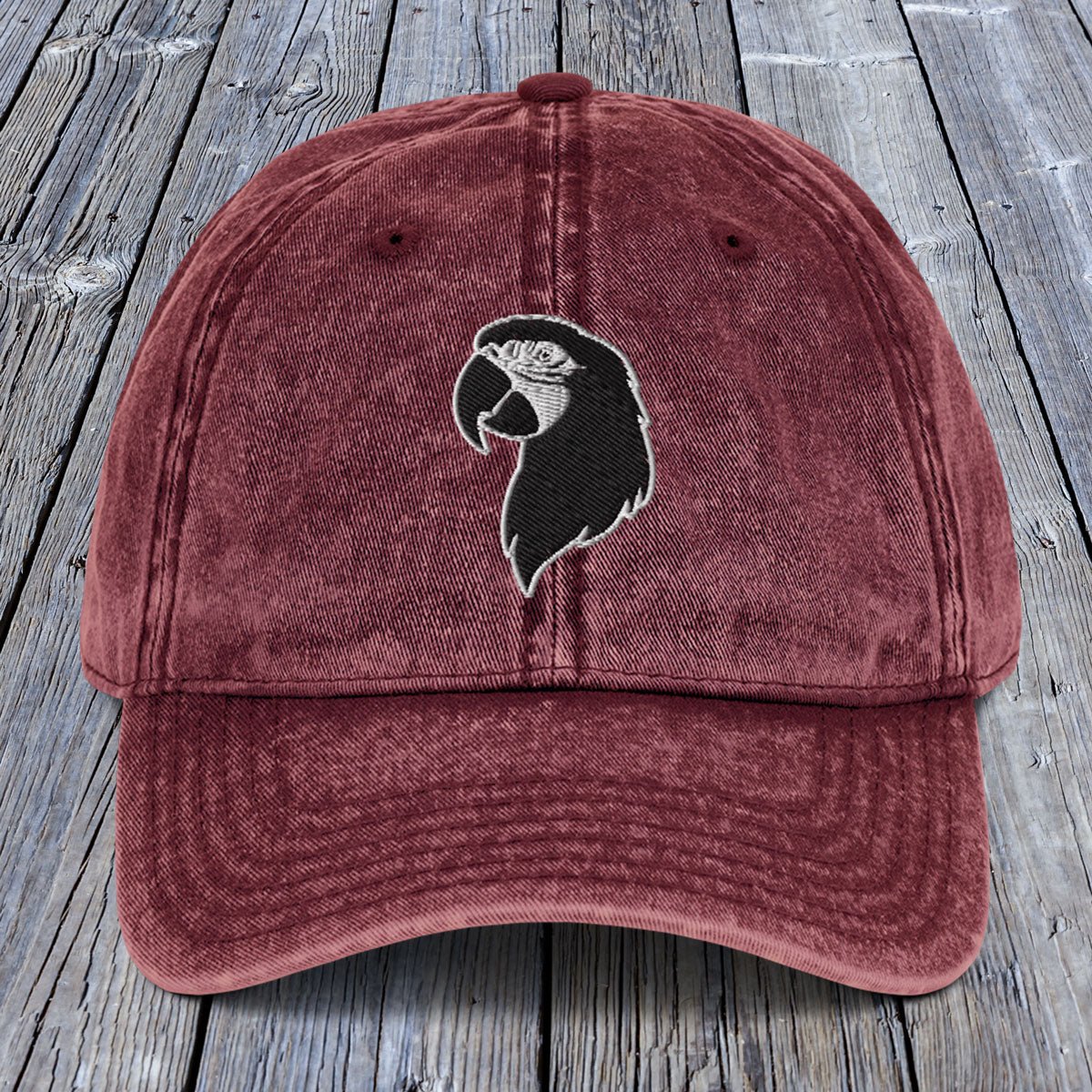 Maroon cap with a black and white logo on a wooden surface