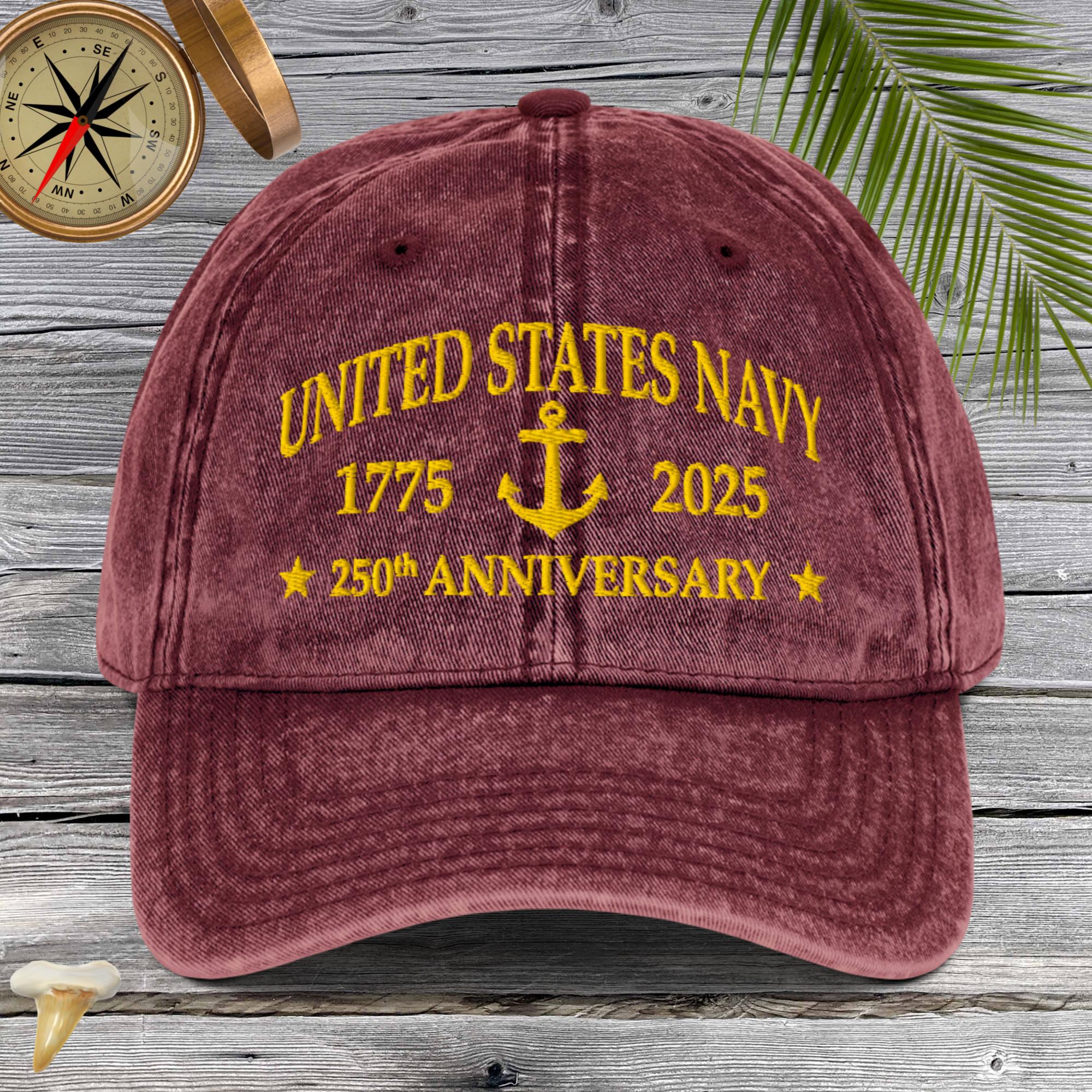 Maroon cap with yellow 'United States Navy 1775-2025 250th Anniversary' text on a wooden background