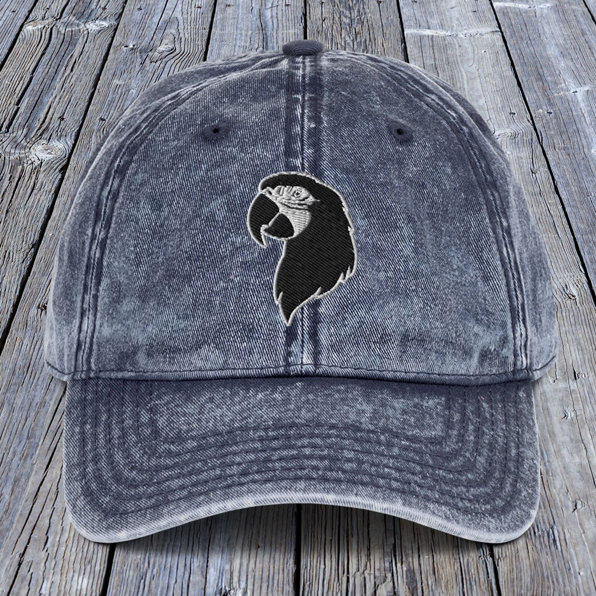 Blue denim cap with a black and white logo on a wooden surface