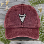 Maroon cap with Embroidered Shark Tooth design on a wooden background with palm leaves