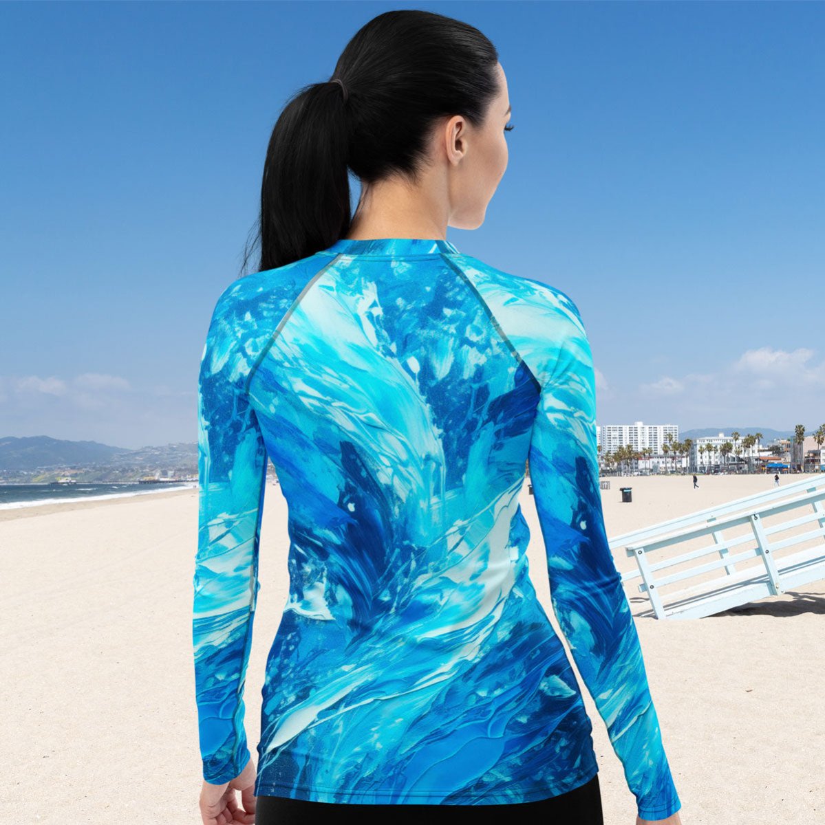 Person wearing a blue and white ragdolled long-sleeve rash guard swim shirt on a beach.