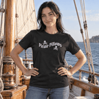A woman wearing a black crewneck t-shirt with a white 'Pirate Pillows' text and skull graphic, standing on a wooden sailing ship deck with the sea in the background.