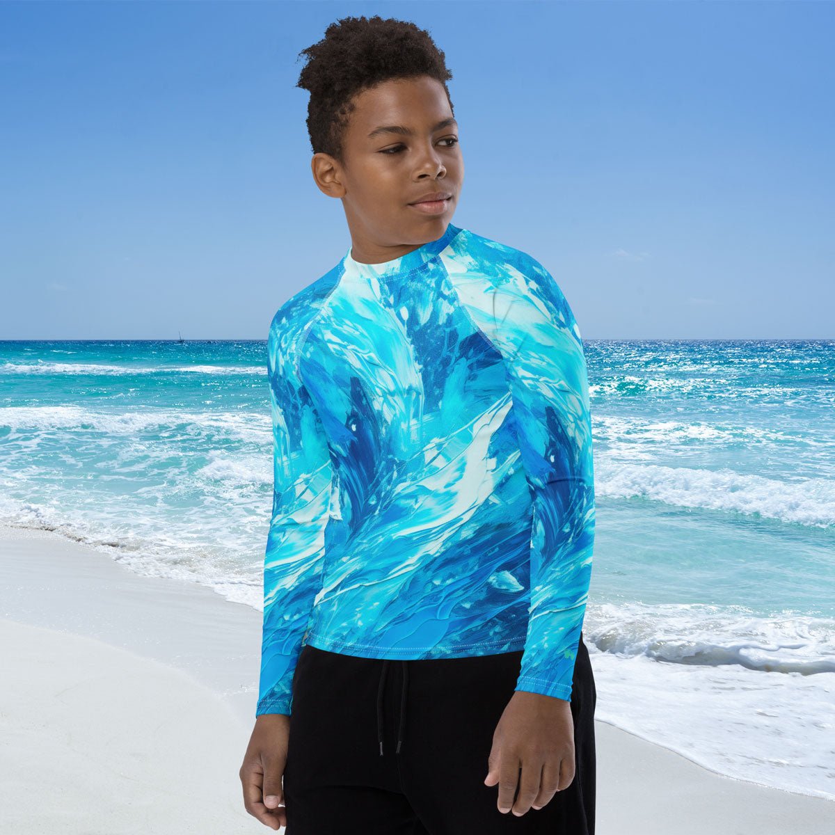 Young dude wearing a blue and white rash guard swimming shirt on a beach