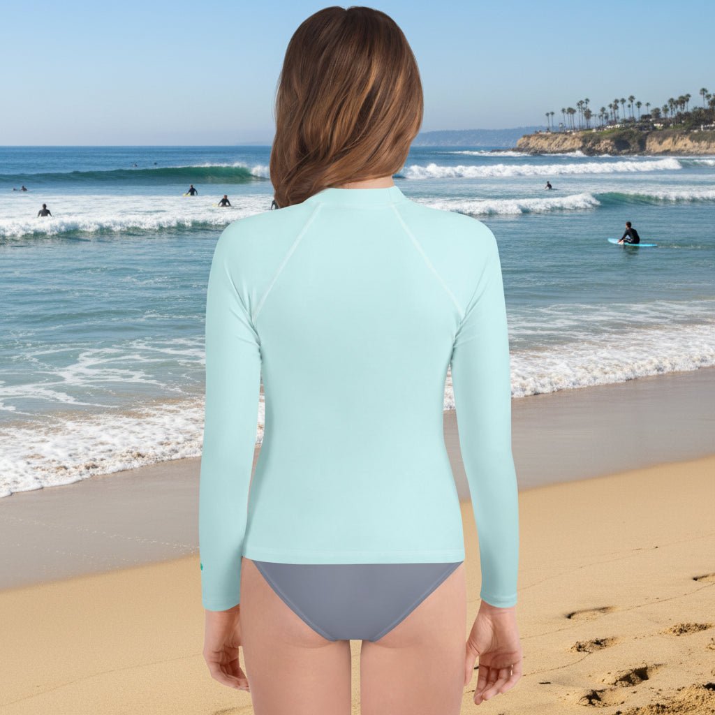 Back side Light blue long-sleeve rash guard worn by a teenage on La Jolla Beach