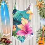 One-piece Hawaiian swimsuit with tropical floral design on a wooden background with beach accessories.
